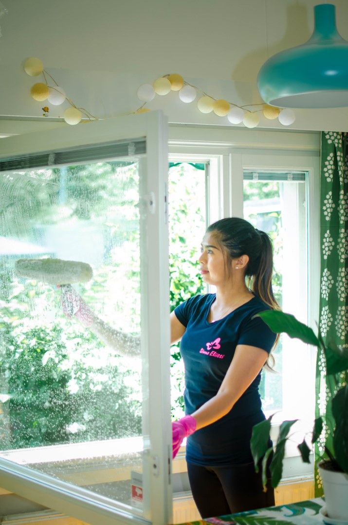 Siivous Eliitin ikkunapesu sisältää kaikkien kodin ikkunoiden pesut. Kuvassa siivousalan ammattilainen pyyhkii ja pesee asiakkaan olohuoneen ikkunaa.